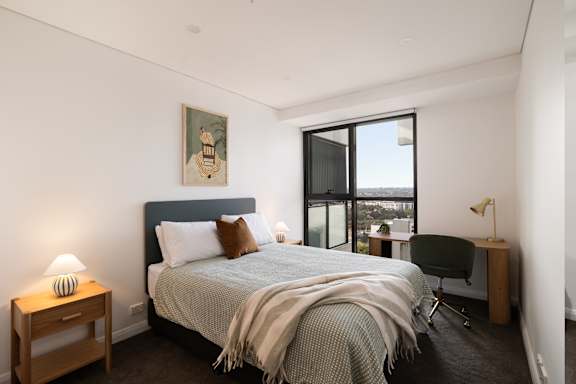 A bedroom with a bed, chair, and a painting on the wall.