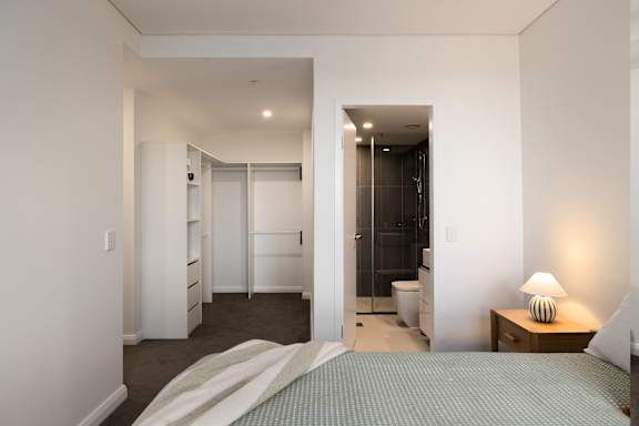 A bedroom with a bed, nightstand, and closet.