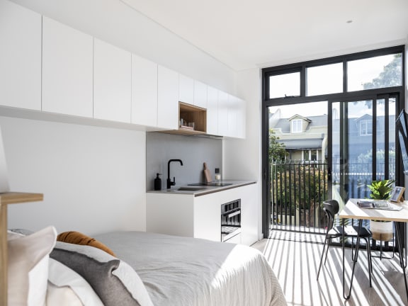 a bedroom with a bed and a kitchen and a balcony
