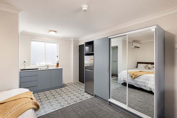 A bedroom with a bed, a dresser, and a mirror.