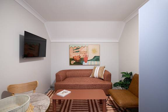 A living room with a brown couch and a painting on the wall.