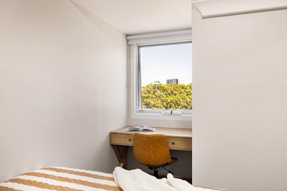 A bedroom with a bed, desk, and chair.