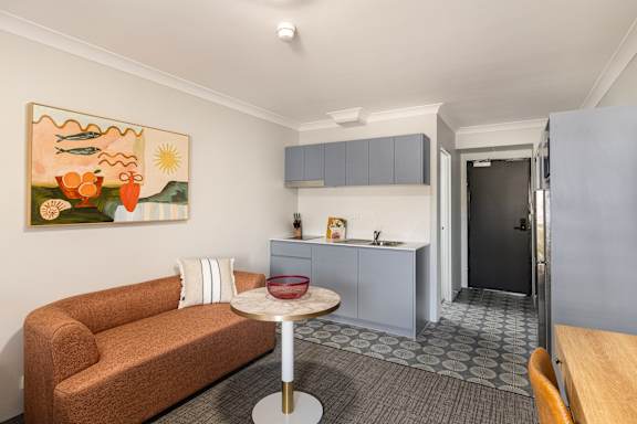 A living room with a brown couch and a painting on the wall.