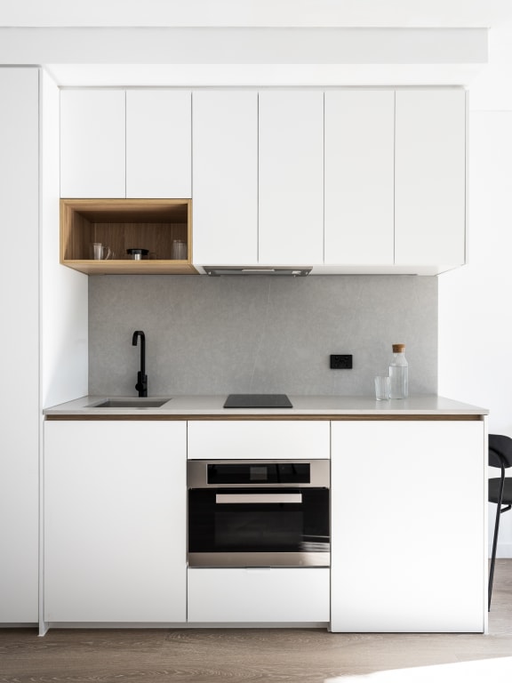 a white kitchen with white cabinets and a black counter top