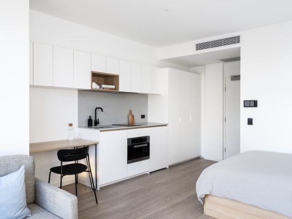 a bedroom with a bed and a kitchen with white cabinets