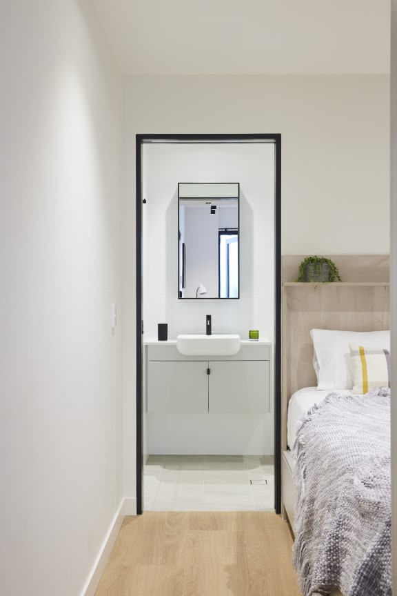 a bathroom with a sink and a mirror in a bedroom