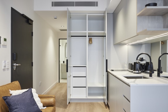 a small kitchen with a refrigerator and a sink and an open closet