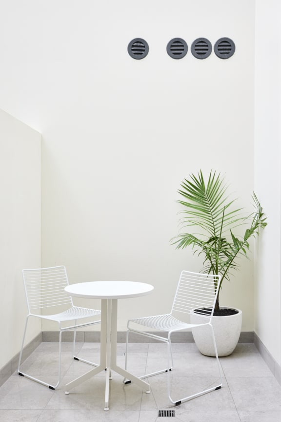 a white table with white chairs and a plant in a room