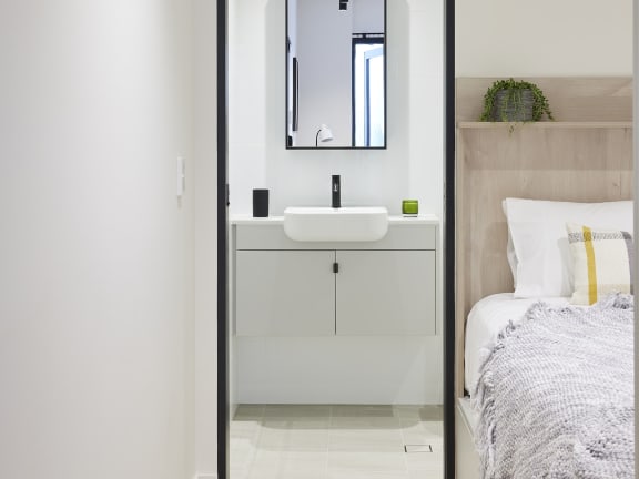 a bathroom with a sink and a mirror and a bed