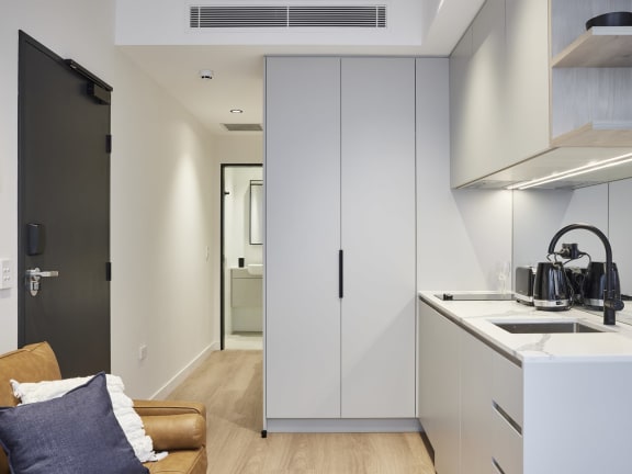 a kitchen and living room with white cabinets and a counter top and a sink