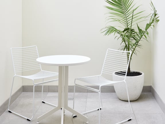 a white table with two chairs and a potted plant