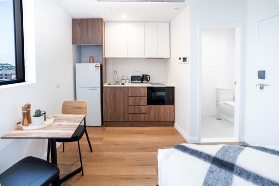 a kitchen and living room with a small table and a refrigerator