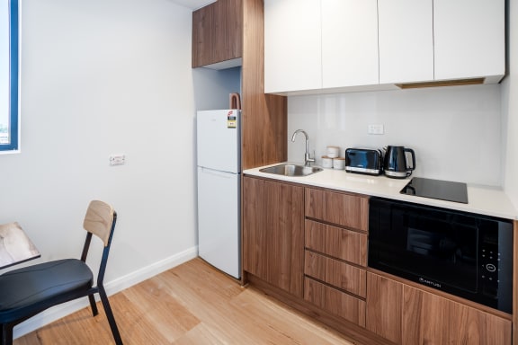 a kitchen with a sink and refrigerator and a chair