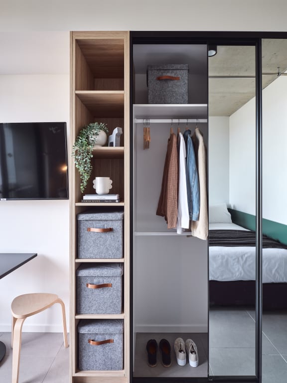 a wardrobe with three drawers and a door open to a room with a bed