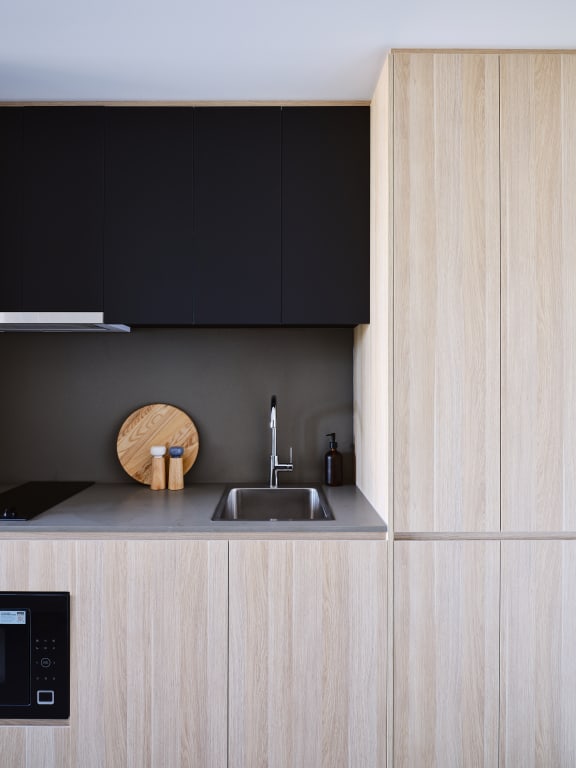 a kitchen with wooden cabinets and a sink and black cabinets