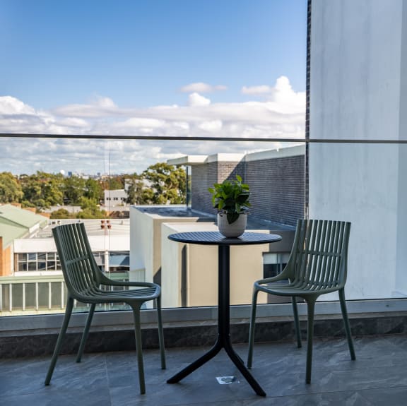 a table with two chairs and a potted plant on a balcony