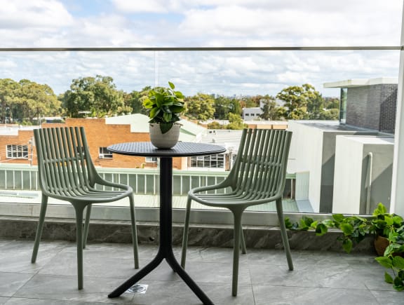 a balcony with two chairs and a table with a potted plant