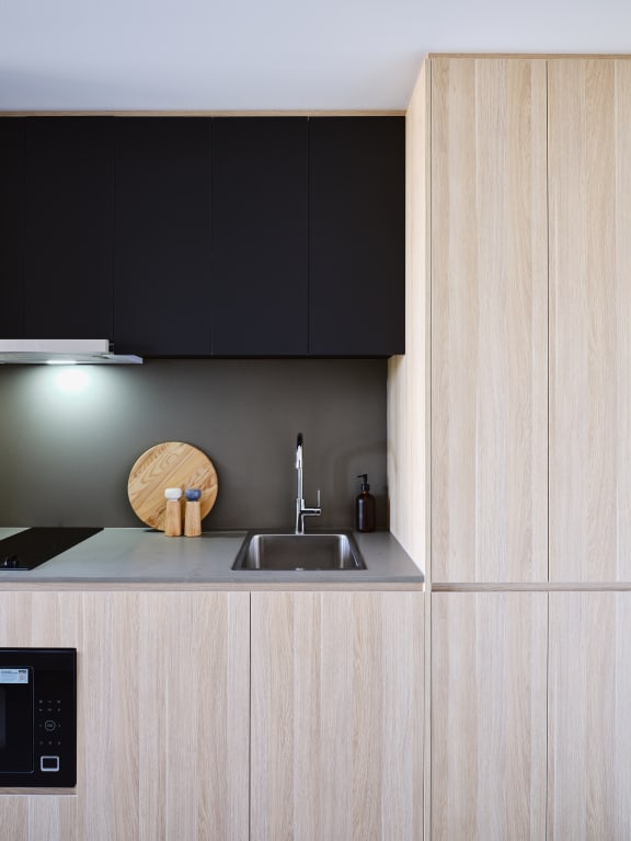 a kitchen with wooden cabinets and a sink and black cabinets