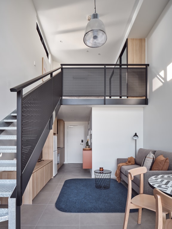 a living room with a staircase and a blue rug