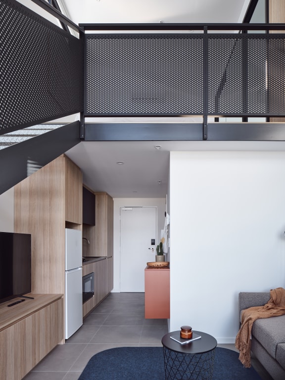 a lofted bedroom with a bed and a kitchen in a small space