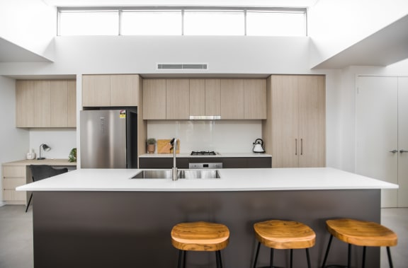 a kitchen with three wooden stools in front of a counter top