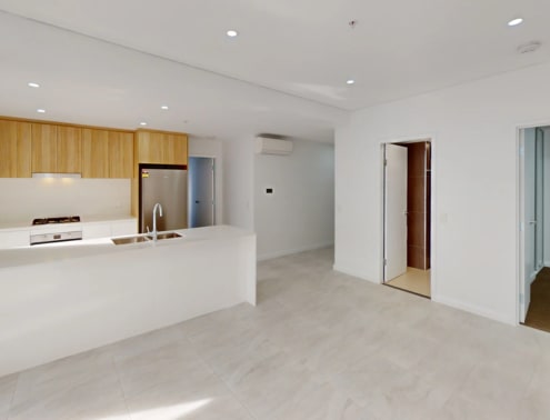 A modern kitchen with a white countertop and wooden cabinets.