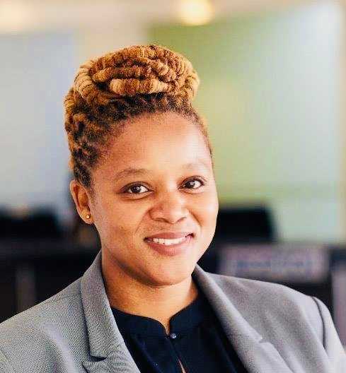 A woman with braided hair wearing a grey blazer and black shirt.