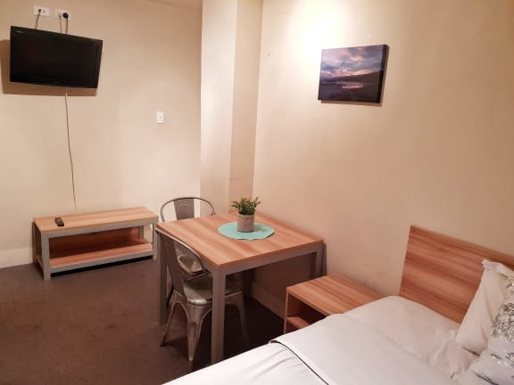 a small room with a bed and a desk and a television