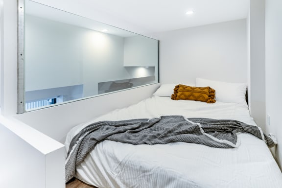 a white bedroom with a bed and a large mirror