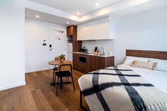 a bedroom with a bed and a kitchen in a 555 waverly studio apartment