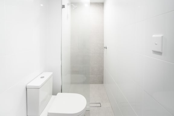 a white bathroom with a toilet and a shower