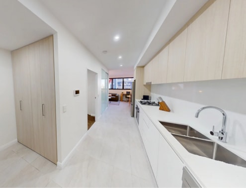 A modern kitchen with white cabinets and a long white counter.