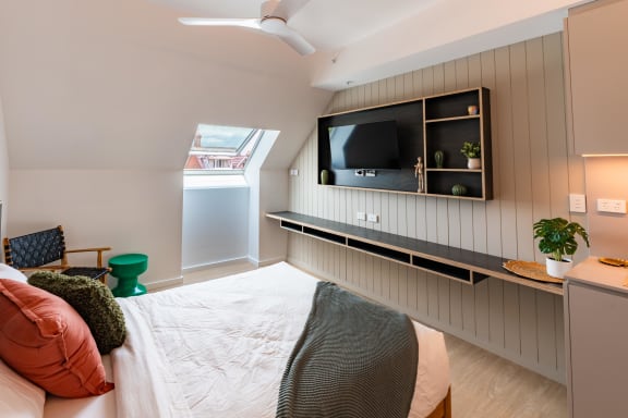 a bedroom with a bed and a tv on the wall