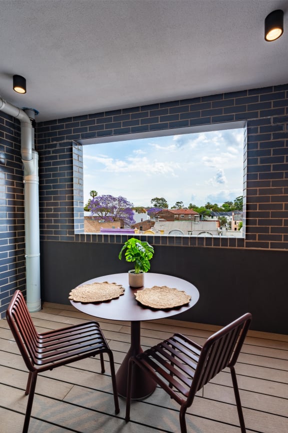 a patio with a table and chairs in front of a window