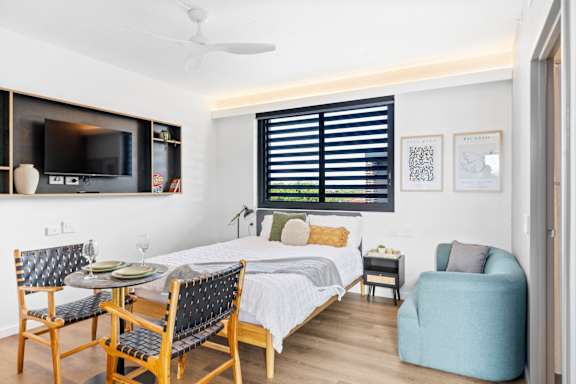 A bedroom with a bed, chair, and a television.