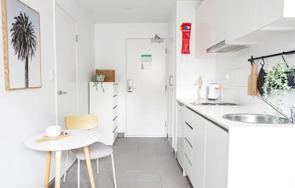 a white kitchen with a small table and a sink