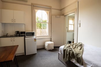 a bedroom with a bed and a refrigerator and a sink