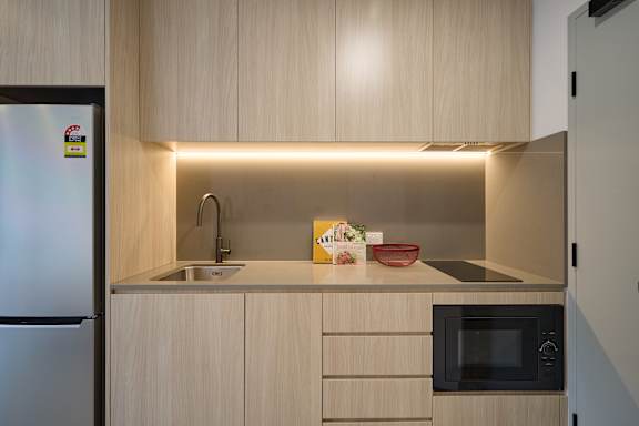 A modern kitchen with a refrigerator, sink, and microwave.
