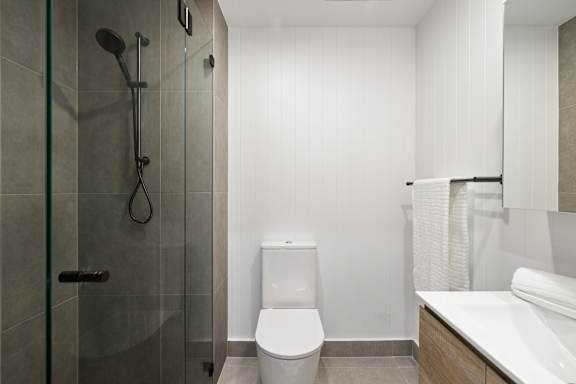 A white toilet sits in a bathroom next to a glass shower stall.