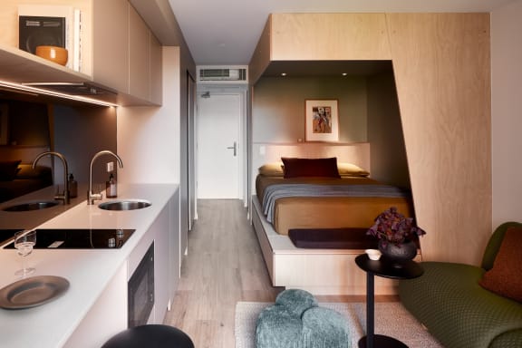 a small hotel room with a bed and a kitchen