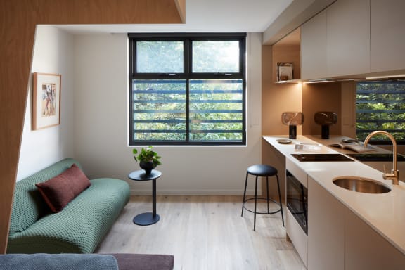 a small living room with a green couch and a kitchen
