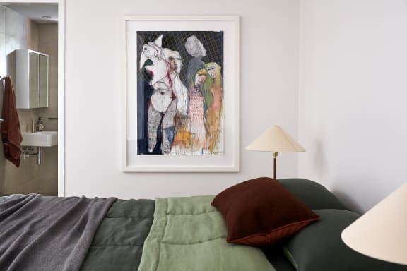 a living room with a bed and a painting on the wall
