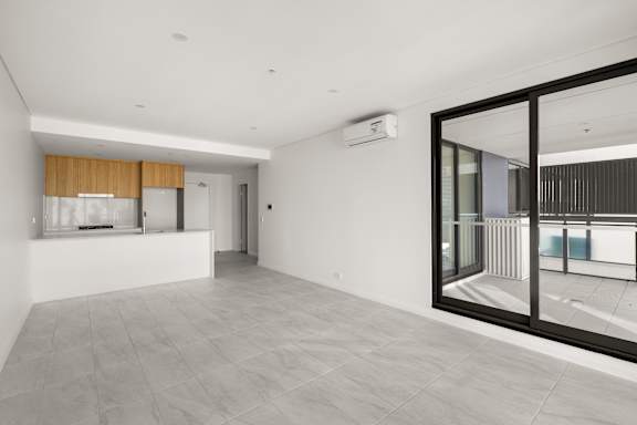 A spacious room with a sliding glass door leading to a balcony.