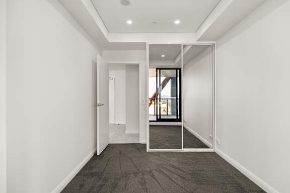 A hallway with a carpeted floor and white walls.