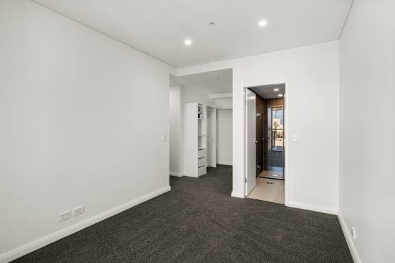 A room with white walls and a grey carpet.