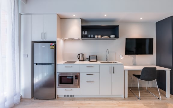 a small kitchen with white cabinets and a stainless steel refrigerator