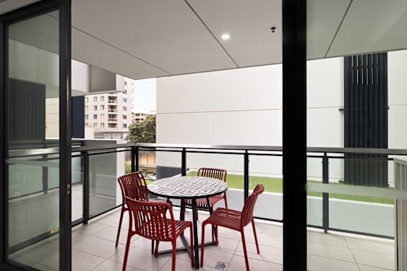 A balcony with a table and chairs overlooking a building.