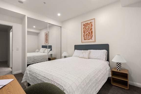 A bedroom with a large bed and a painting on the wall.