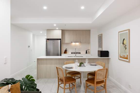A modern kitchen with a dining table set for two.