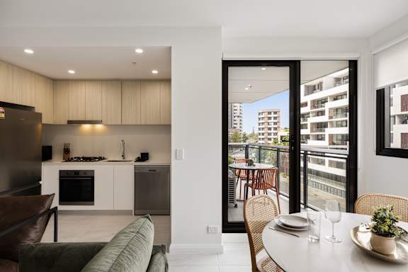 A modern kitchen with a dining table set for two.